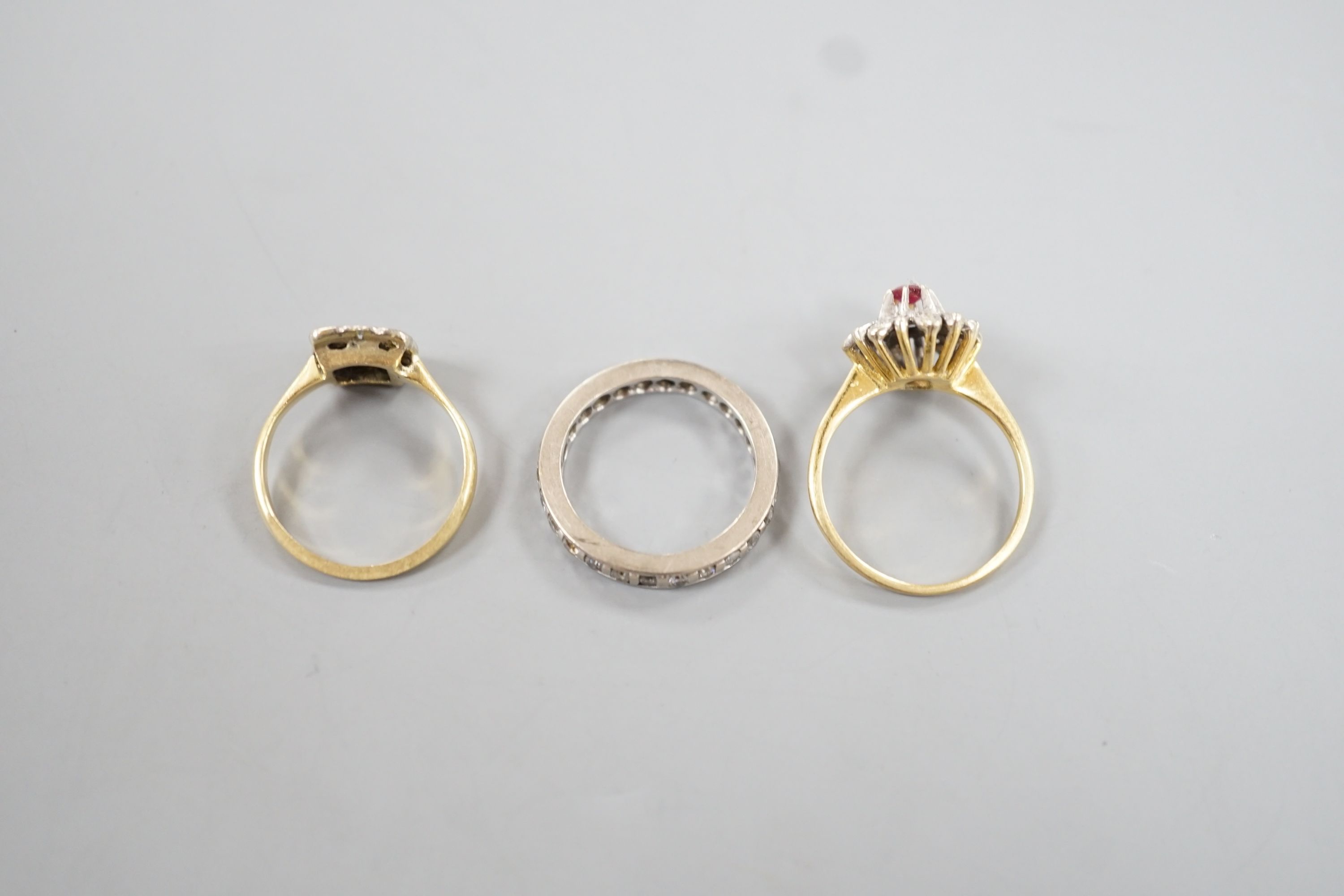 A white metal an diamond chip set full eternity ring, size J/K, gross 3.4 grams, a 1920's 18ct and nine stone diamond set tablet ring, size K/L, gross 2.4 grams and a yellow metal and gem set cluster ring, gross 3 grams.